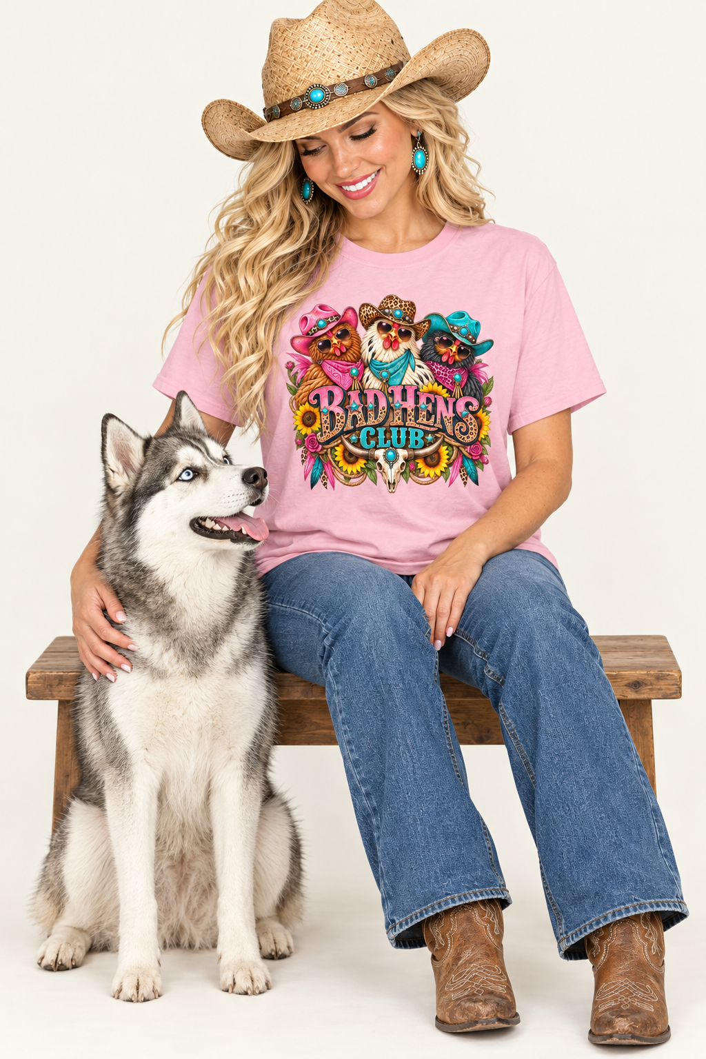 Cowgirl wearing the pink Bad Hens Club tee seated beside a husky in a clean studio