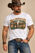 Single cowboy portrait in the white Pasture Raised tee on a clean cream studio backdrop