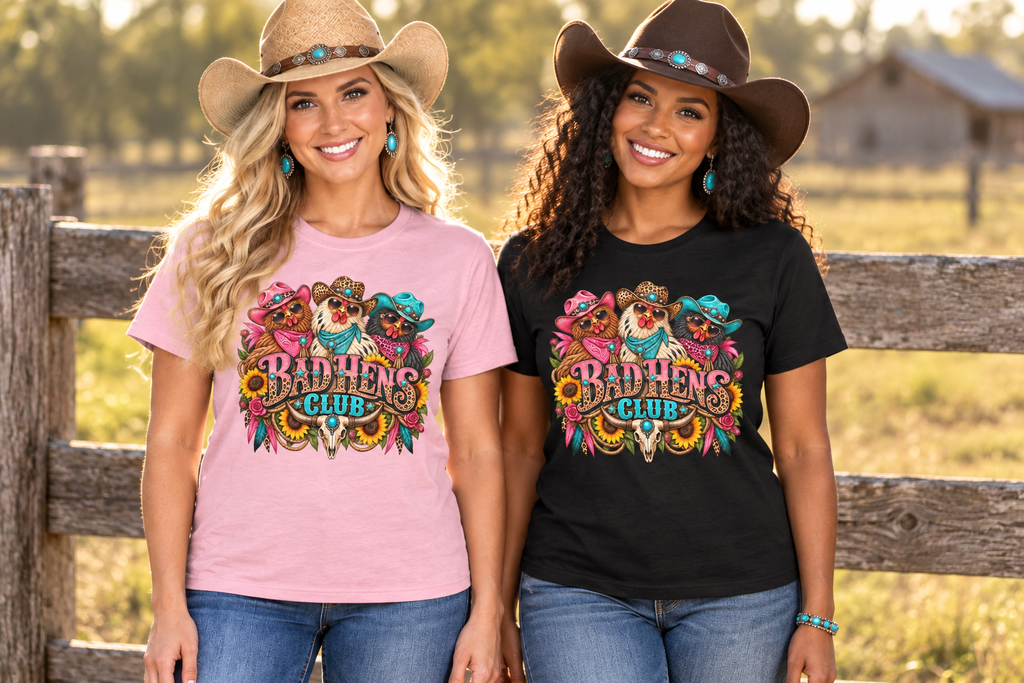 Two cowgirl besties wearing pink and black Bad Hens Club tees beside a ranch fence